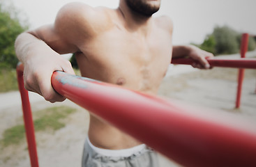 Image showing young man exercising on parallel bars outdoors