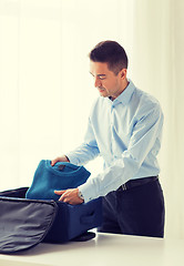 Image showing businessman packing clothes into travel bag