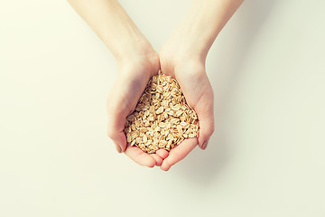 Image showing close up of woman hands holding oatmeal flakes