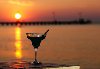 Image showing Tropical cocktail overlooking a sunset ocean