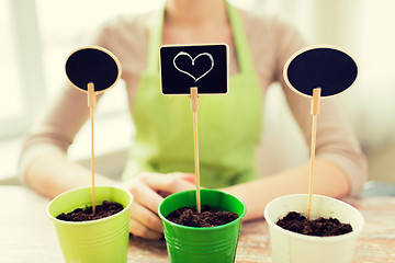 Image showing close up of woman over pots with soil and signs