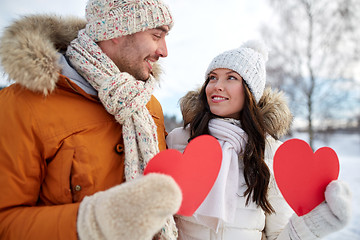 Image showing happy couple with red hearts over winter landscape