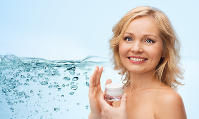 Image showing happy woman applying cream to her face