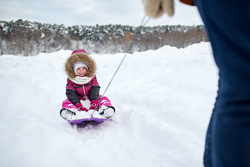 Image showing parent carrying happy little kid on sled in winter