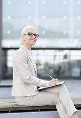 Image showing young smiling businesswoman with notepad outdoors