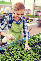 Image showing woman with sprayer and seedling in greenhouse