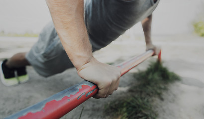 Image showing young man exercising on horizontal bar outdoors