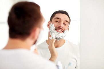 Image showing happy man applying shaving foam at bathroom mirror