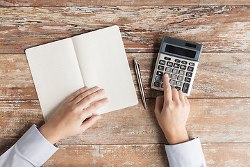 Image showing close up of hands with calculator and notebook