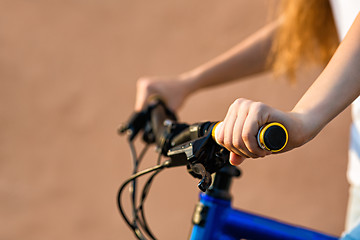 Image showing The hands of young woman sitting on bicycle