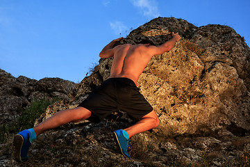 Image showing Young man climbing the mountain ridge