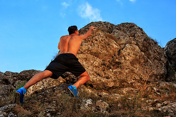 Image showing Young man climbing on a wall