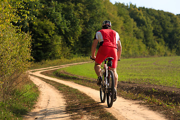 Image showing Man is cycling in autumn forest