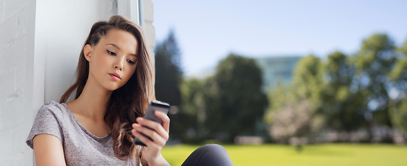 Image showing sad pretty teenage girl with smartphone texting