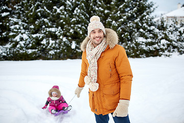 Image showing happy man carrying little kid on sled in winter