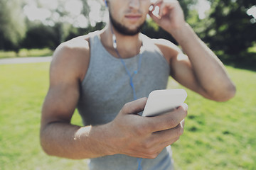 Image showing young man with earphones and smartphone at park