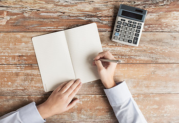 Image showing close up of hands with calculator and notebook