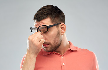 Image showing tired man with eyeglasses touching nose bridge