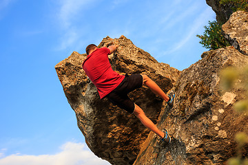 Image showing Young man climbing on a wall