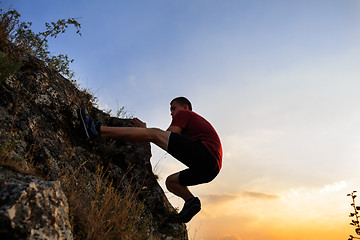 Image showing Young man climbing on a wall