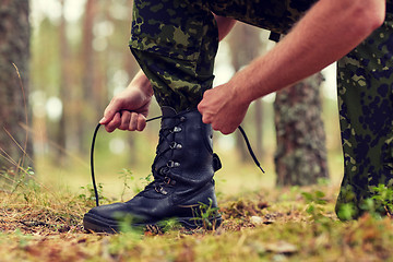 Image showing close up of soldier tying bootlaces in forest