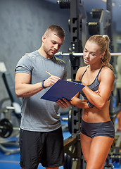 Image showing young woman with personal trainer in gym