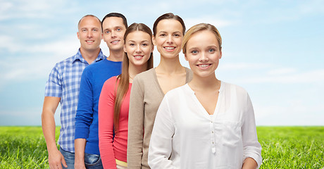 Image showing group of smiling people over blue sky and grass