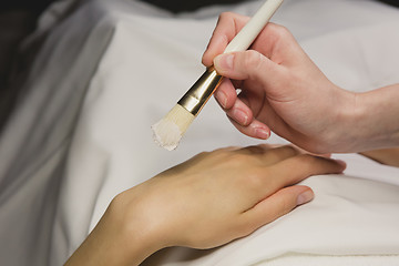Image showing Close up of hands applying cream over table