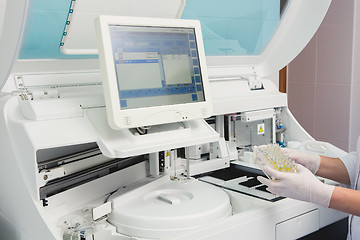 Image showing Lab tech loading samples into a chemistry analyzer