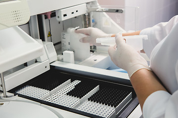 Image showing Lab tech loading samples into a chemistry analyzer