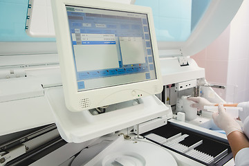 Image showing Lab tech loading samples into a chemistry analyzer