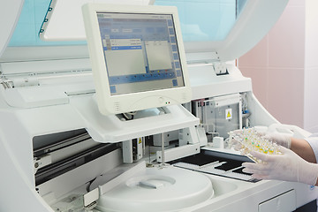 Image showing Lab tech loading samples into a chemistry analyzer