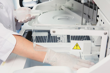 Image showing Lab tech loading samples into a chemistry analyzer