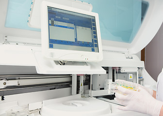 Image showing Lab tech loading samples into a chemistry analyzer