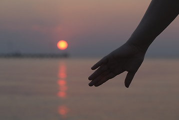 Image showing Womans hand silhouetted against a sunset