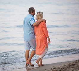 Image showing Senior couple enjoying barefoot walk at the seaside