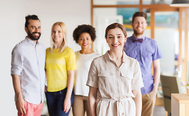 Image showing happy young woman over creative team in office