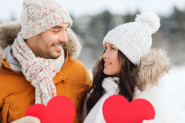 Image showing happy couple with red hearts over winter landscape