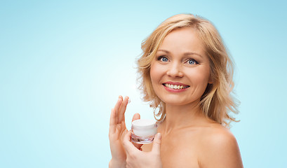 Image showing happy woman applying cream to her face