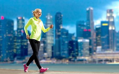 Image showing happy woman jogging over city street background