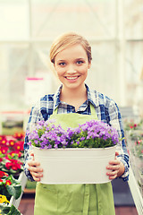 Image showing happy woman holding flowers in greenhouse