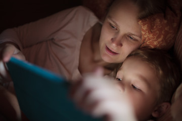 Image showing Mother and son with pad in bed at night