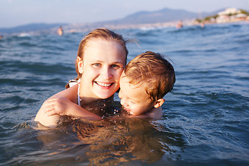 Image showing Happy mother teaching her young son to swim