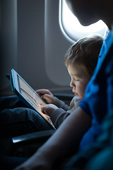 Image showing Little boy playing with a tablet in an airplane