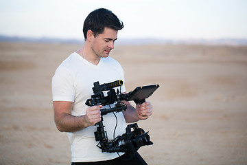 Image showing Young man using steadycam for shooting on beach