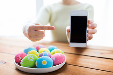 Image showing close up of hands with easter eggs and smartphone