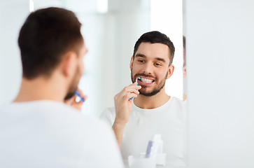 Image showing man with toothbrush cleaning teeth at bathroom