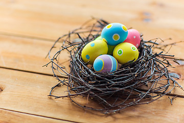 Image showing close up of colored easter eggs in nest on wood