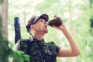 Image showing young soldier with gun and flask in forest