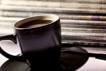 Image showing Cup of coffee and newspapers pile on the table.